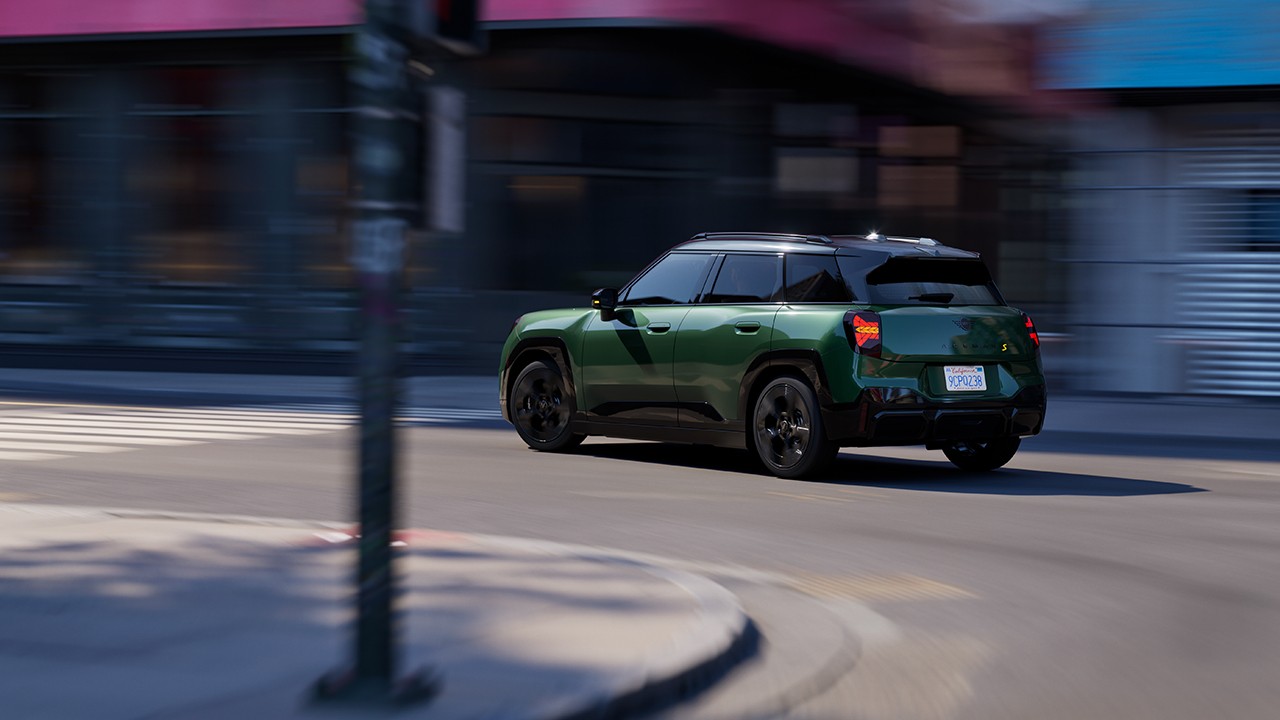 Exterior view of all-electric MINI Aceman with open door and MINI logo welcome light on the ground 